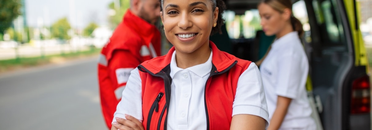 Smiling EMS professional in front of an ambulance