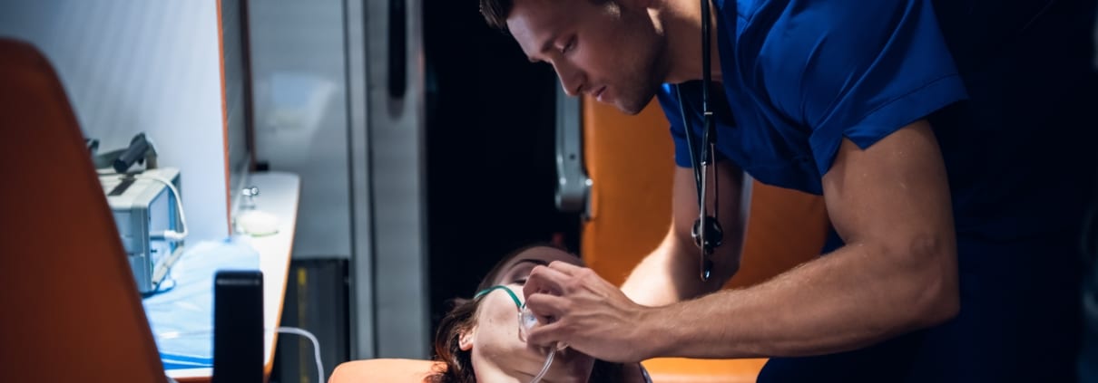Male EMS professional placing an oxygen mask on a woman