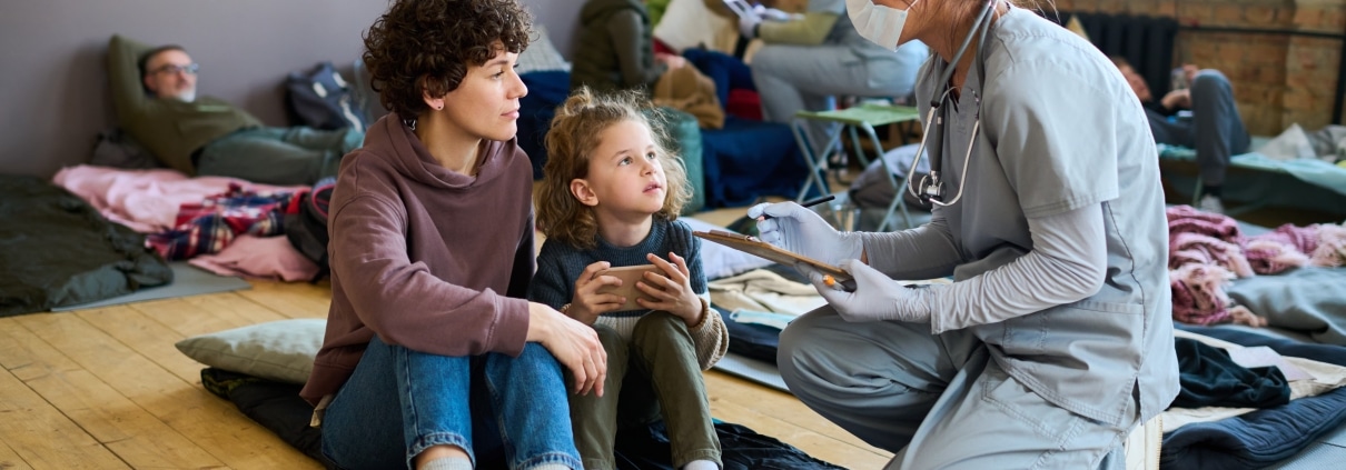 Medical professional kneeling next to a homeless woman and child