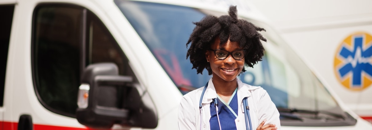 Smiling African-American EMS professional in front of an ambulance